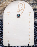 The Jamie Stud Fashion Earring on a measuring board on beans and wheat.