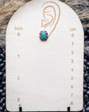 The Jamie Stud Fashion Earring on a measuring beard, sitting on beans and wheat.
