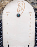 The Jamie Stud Fashion Earring on a measuring beard, sitting on beans and wheat.
