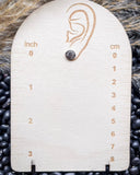 The Jamie Stud Fashion Earring on a measuring board, sitting on beans and wheat.