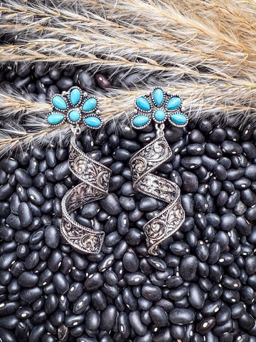 Filigree spiral earrings with turquoise flowers on rustic background.