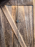 Silver and turquoise bolo tie hanging on rustic wooden barn door background