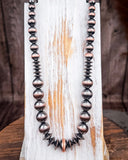 Southwestern oxidized bead necklace with brushed copper accents on rustic wood display.