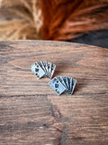 Stud earrings displayed on wood with grass in the background