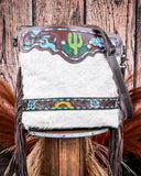Handbag with decorative panels and grey fur on a wooden stool against a wooden background