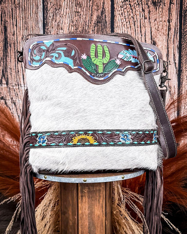 Handbag with decorative panels and grey fur on a wooden stool against a wooden background