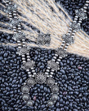 Necklace and earrings displayed on wheat and beans.