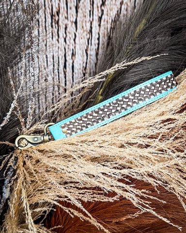 Teal Accent Hand-Tooled Strap Key Fob displayed on wheat, wood backdrop.