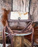 Front view of the Carved Blossoms Leather & Hairon Bag displayed on a table, wood back drop.