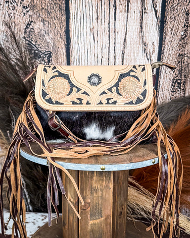 Front view of the Coral Paz Hand-Tooled Bag on a wood table with a wood back drop.