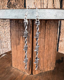 Silver twisted wire earrings on a wooden block.