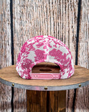 Back view of the Country Club Pink Cow Print Trucker Cap displayed on a wood table, wood backdrop.