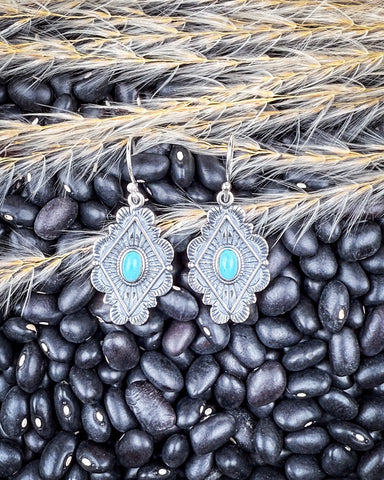 The Leif Genuine Turquoise Earrings displayed on beans and wheat.