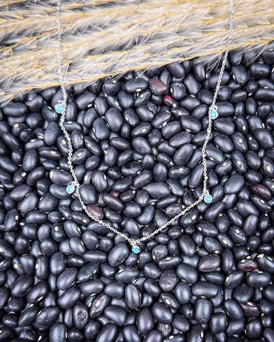 The Alana Turquoise Shaker Necklace displayed on beans and wheat.