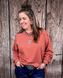 The Stillwater Tunic Top in color Rust being styled and modeled on women in front of wood backdrop.