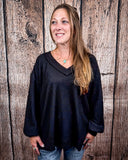 The Hadley Top in black styled and modeled on women in front of wood background.