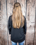 The Hadley Top in black styled and modeled on women in front of wood background.