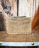 The Outlander Edge Credit Card Holder in Brown displayed on a wooden table with wheat behind it, sitting in front of a wood backdrop.