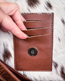 Zoom in of the clasp on the Straybird Hair on Hide Fringe Crossbody Bag. There is 3 slits above it, 3 fingers are opening the slits.