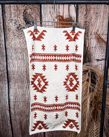 The Terra Sands Towel, clipped to a hanger that is hanging from a metal rod with wheat behind it in a wood back ground.