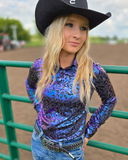 Person wearing a colorful long-sleeve shirt and black cowboy hat in an outdoor setting.