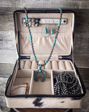 The Myra Bag - Mausoleum Jewelry Box open to show the jewelry inside. It is sitting on a wooden table with wood paneling.