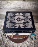 The Myra Bag - Mausoleum Jewelry Box sitting on a wooden wire wheel with jewelry hanging out of the opening. the table is on gray carpet.
