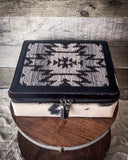 The Myra Bag - Mausoleum Jewelry Box sitting on a wooden wire wheel. The table is on gray carpet