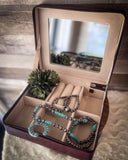 The inside of the Statuesque Jewelry Box showing the compartments and jewelry that is inside along with a plant.