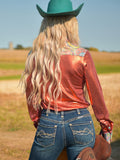 Woman wearing a rust metallic long sleeve button up shirt with colorful paisley trim