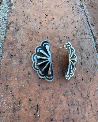 Decorative earrings on a textured brick surface