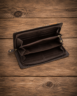 An open black leather wallet with multiple card slots and a zip compartment, displayed on a rustic wooden surface.