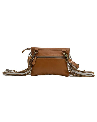 A brown leather crossbody bag with a front zip pocket and a long, fringed strap in brown, beige, and white, shown against a plain white background.