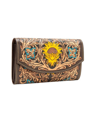 A brown leather wallet with hand-tooled floral and scroll patterns, featuring a large yellow sunflower design on the front flap.