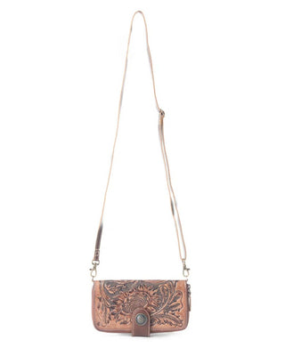 A brown tooled leather crossbody bag with an intricate floral design, a long adjustable strap, and a snap closure, shown against a plain white background.
