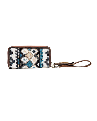 A zip-around wallet with a geometric Southwestern-style woven pattern in black, white, beige, and teal, featuring brown leather trim and a matching wristlet strap with a tassel.