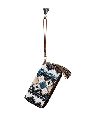 A zip-around wallet with a Southwestern geometric pattern in blue, beige, black, and white, featuring a brown leather wrist strap and tassel.