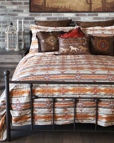 Bedroom with a bed featuring a patterned comforter and pillows, against a brick wall.