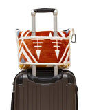 Patterned travel blanket on a suitcase handle with a white background