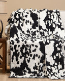 Black and white patterned blanket draped over a chair in a room with a lamp and small table.