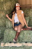 Woman sitting on hay bales wearing a puffer vest and shorts