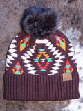 The Aztec Pom Beanie displayed on cowhide.