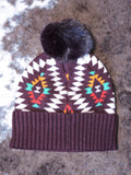 The Aztec Pom Beanie displayed on cowhide.