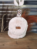 The Aztec Earmuff displayed on a wooden table in front of a metal wall with wheat in the back ground.