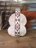 Top view of the Aztec Earmuff to show the design, displayed on a wooden table with wheat in the back ground.