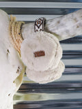 The Aztec Earmuff hanging from a cow skull horn in front of a metal wall.