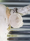 The Aztec Earmuff hanging from a cow skull horn in front of a metal wall.