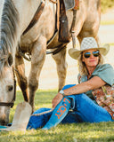 Model posing in the grass wearing the Lucky Denim Performance Socks with a horse in the back ground.