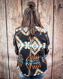 Person wearing a patterned jacket against a wooden background