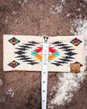 The Aztec Head Wrap, shown on a cowhide backdrop with a ruler indicating it measures about 4 inches wide.